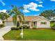 Charming beige home with a manicured lawn, palm tree, and a lovely landscaped front yard at 9131 Se 135Th St, Summerfield, FL 34491