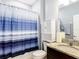 Well-lit bathroom featuring a granite vanity, cabinet, toilet, and shower with a blue-striped curtain at 9237 Sw 60Th Terrace Rd, Ocala, FL 34476