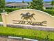A decorative stone and stucco community sign with horse art set amongst lush landscaping at 9237 Sw 60Th Terrace Rd, Ocala, FL 34476