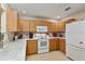 Well-lit kitchen featuring wood cabinetry, a marble countertop, and a suite of white appliances at 9290 Sw 89Th Ter # D, Ocala, FL 34481