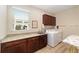 Well-lit laundry room featuring wooden cabinetry, granite counters, and a modern washer and dryer set at 9607 Sw 79Th Lane Rd, Ocala, FL 34481