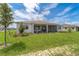 Exterior view of the house featuring a green lawn and screened-in patio at 10553 Sw 98Th Pl, Ocala, FL 34481