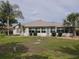 Back of the house with large, green yard, shrubs, and palm trees at 13863 Se 85Th Cir, Summerfield, FL 34491