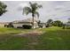The back of a light-colored house with a well-kept lawn, landscaping, and mature palm trees at 13863 Se 85Th Cir, Summerfield, FL 34491