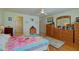 Bright bedroom featuring a ceiling fan, wood floors, and a large dresser with mirror at 13863 Se 85Th Cir, Summerfield, FL 34491