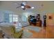 Cozy living room featuring ceiling fan, hardwood floors, and sliding glass doors leading to a sunroom at 13863 Se 85Th Cir, Summerfield, FL 34491