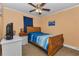 Cozy bedroom with wood furniture, ceiling fan, light orange walls, and blue accents at 14276 Se 61St Ave, Summerfield, FL 34491