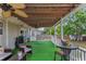 Covered porch with green turf, ceiling fans, and seating and table for outdoor gatherings at 14276 Se 61St Ave, Summerfield, FL 34491