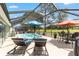 Screened-in pool area with a pool, lounge chairs, outdoor dining set, and views of the golf course at 15119 Sw 14Th Avenue Rd, Ocala, FL 34473
