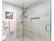 Modern walk-in shower featuring neutral-toned tiles, glass enclosure, and a built-in shelf for toiletries at 15119 Sw 14Th Avenue Rd, Ocala, FL 34473
