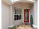 Inviting covered front porch with a red door, window, and decorative plants at 1748 Sw 157Th Place Rd, Ocala, FL 34473