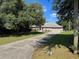 Charming home with a well-maintained lawn, mature trees, and a long driveway leading to a two-car garage at 21 Pecan Course Cir, Ocala, FL 34472