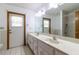Bright bathroom features double sinks, large mirror, tile floors, and door leading to the outside at 3295 Se 56 Ave, Ocala, FL 34480