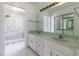 Modern bathroom featuring double sinks, white cabinets, large mirror, and walk-in shower with marble surround at 3295 Se 56 Ave, Ocala, FL 34480