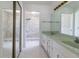 Bright bathroom with double sinks, white cabinets, large mirror, and walk-in shower with marble surround at 3295 Se 56 Ave, Ocala, FL 34480