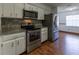 Updated kitchen with stainless steel appliances, granite counters, mosaic tile backsplash, and wood-look flooring at 3295 Se 56 Ave, Ocala, FL 34480