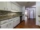 Open kitchen featuring white cabinetry, stainless appliances, granite counters, and wood-look flooring at 3295 Se 56 Ave, Ocala, FL 34480