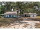 Inviting single-story blue home with a two-car garage, set back from the street amidst lush greenery at 3823 Se 49Th St, Ocala, FL 34480