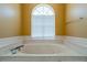 Large soaking tub with marble surround and a window providing natural light in the bathroom at 5815 Ne 70Th St, Silver Springs, FL 34488