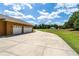 Exterior view of home featuring large three-car garage, long driveway, and well-manicured landscape at 5815 Ne 70Th St, Silver Springs, FL 34488