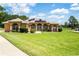 Charming tan stucco home featuring arched windows, manicured landscaping, green lawn and solar panels at 5815 Ne 70Th St, Silver Springs, FL 34488
