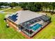 Aerial view of home showcasing a large screened-in pool enclosure and solar panels at 5815 Ne 70Th St, Silver Springs, FL 34488