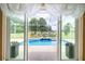 A beautiful inground pool and backyard view is seen through sliding glass doors and a decorative valance at 5815 Ne 70Th St, Silver Springs, FL 34488