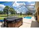A covered outdoor area boasts a relaxing hot tub and inground pool with an outdoor lounging area at 5815 Ne 70Th St, Silver Springs, FL 34488