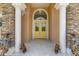 Elegant front entryway with columns and stone accents leading to a cheerful yellow door at 6573 S Magnolia Ave, Ocala, FL 34471
