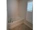Bathroom features a soaking tub with tile surround and a window with shutters at 6836 Sw 179Th Court Rd, Dunnellon, FL 34432