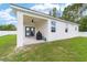 View of the home's white stucco exterior with a covered patio and well maintained lawn at 7479 Sw 130Th Ln, Ocala, FL 34473