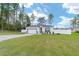 Landscaped lawn featuring a driveway leading to a white single-story home with an attached garage at 7479 Sw 130Th Ln, Ocala, FL 34473