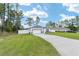 Landscaped lawn featuring a driveway leading to a white single-story home with an attached garage at 7479 Sw 130Th Ln, Ocala, FL 34473