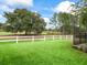 The backyard features a well-maintained lawn, mature trees, and a white fence bordering the golf course at 8447 Sw 82Nd Loop, Ocala, FL 34481