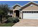 Charming single-story home featuring a brick driveway, two-car garage, and a well-manicured lawn with flowering bushes at 8447 Sw 82Nd Loop, Ocala, FL 34481