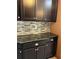 Stylish kitchen featuring dark cabinetry, granite countertops, and a mosaic backsplash, creating a modern aesthetic at 8447 Sw 82Nd Loop, Ocala, FL 34481