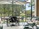 A screened-in patio with comfortable seating, a dining table, and views of the golf course and lush greenery at 8447 Sw 82Nd Loop, Ocala, FL 34481