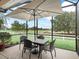 A screened-in patio with dining table and umbrella overlooks a lush, green golf course at 8447 Sw 82Nd Loop, Ocala, FL 34481