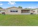 Large backyard featuring a lush lawn with mature trees and exterior view of a screened patio at 8885 Sw 90Th Ave, Ocala, FL 34481