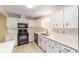 Well-lit kitchen with white cabinets, black appliances, and tile floors at 8885 Sw 90Th Ave, Ocala, FL 34481