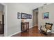 Hallway featuring hardwood floors, neutral walls decorated with pictures, and a decorative cabinet at 9175 Se 7Th Avenue Rd, Ocala, FL 34480