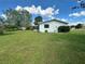 Charming home exterior with a well-maintained lawn, mature shrubbery, and a view of the side yard at 10080 Sw 97Th Ct, Ocala, FL 34481