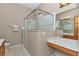 A full bathroom features a glass shower with a bench, marble countertop, tile floor, and oak cabinet at 11062 Sw 73Rd Ct, Ocala, FL 34476