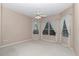 A spacious bedroom features neutral walls, carpet, a ceiling fan, and windows dressed with white curtains at 11062 Sw 73Rd Ct, Ocala, FL 34476