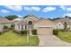 Inviting home featuring a well-manicured lawn, neatly trimmed shrubs, and a spacious driveway leading to an attached garage at 11062 Sw 73Rd Ct, Ocala, FL 34476