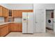 Spacious kitchen features wood cabinets, white appliances, and view of the laundry room at 11062 Sw 73Rd Ct, Ocala, FL 34476