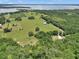 Beautiful aerial view showcasing the property's expansive land, trees, and a distant lake at 12080 Se Sunset Harbor Rd, Weirsdale, FL 32195