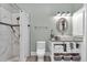 Bathroom with a marble tile shower, modern vanity, decorative mirror, and ample towel storage at 12080 Se Sunset Harbor Rd, Weirsdale, FL 32195