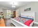 Bright bedroom features wood floors, a chandelier, and a comfortable bed with a colorful quilt at 12080 Se Sunset Harbor Rd, Weirsdale, FL 32195