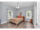 Bright bedroom featuring hardwood floors, a cozy bed, natural light and guitar at 12080 Se Sunset Harbor Rd, Weirsdale, FL 32195
